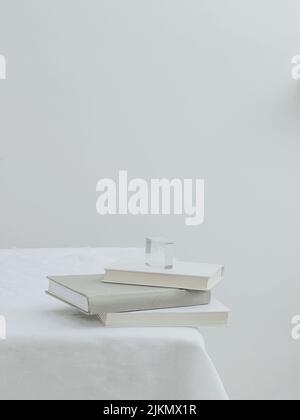 An aesthetic view of three books on a table with white tablecloth Stock Photo