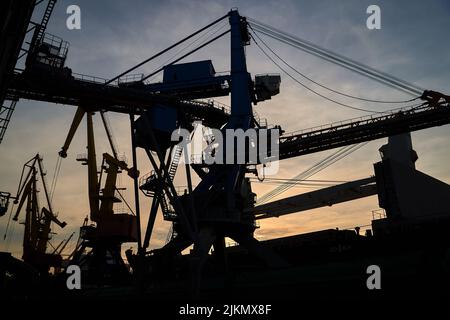 silhouette of port cranes against the backdrop of sunset. Stock Photo