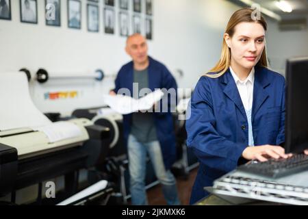 Technician operator calibrating plotter machine, typing on computer keyboard Stock Photo