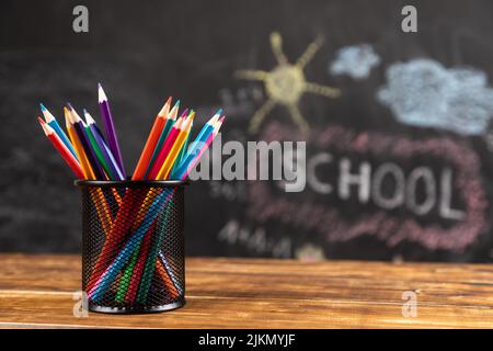 colored pencils on wooden background with chalkboard school Stock Photo