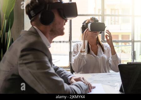 Young entrepreneurs having a metaverse remote meeting using 360 VR googles sitting at the office desk - Business people lifestyle concept Stock Photo