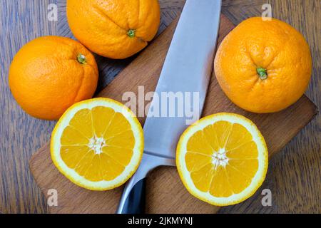 Whole and sliced oranges on a wooden board on the table Stock Photo