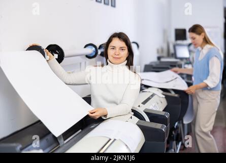 Print worker controlling printing process on modern offset machine in print shop Stock Photo