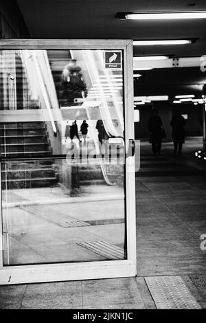 A reflection of walking people in an open glass door in the Kaponiera underground passage. Stock Photo
