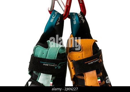 Close-up of climbing shoes (Scarpa Instinct vs) hanging on carabiner against a white background. Colorful climbing equipment from popular company Stock Photo