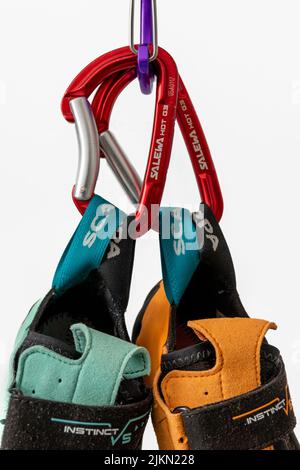 Close-up of climbing shoes (Scarpa Instinct vs) hanging on carabiner against a white background. Colorful climbing equipment from popular company Stock Photo