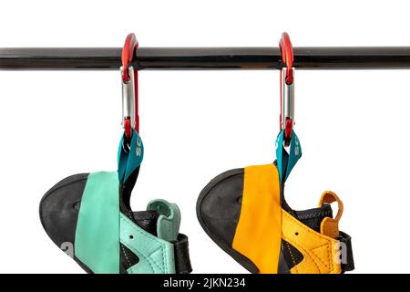 Close-up of climbing shoes (Scarpa Instinct vs) hanging on carabiner against a white background. Colorful climbing equipment from popular company Stock Photo