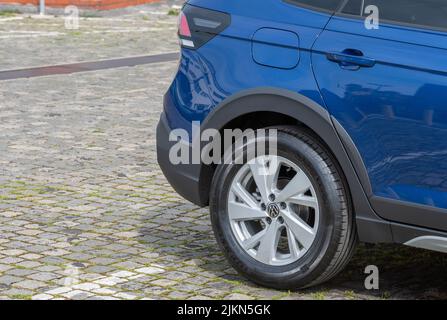 A closeup shot of a black wheel of a blue vehicle parked on the street Stock Photo