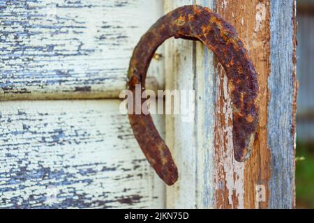 A selective shot of an old rusty horseshoe hanging on a nail on a   wooden wall Stock Photo