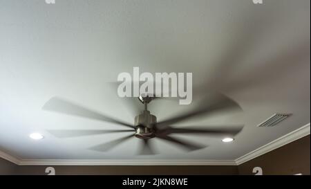 A moving and blurred interior fan inside a new construction house with a white ceiling Stock Photo