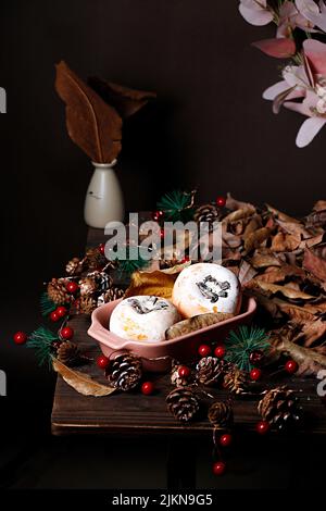 A vertical shot persimmon fruits on a table decorated with pines and dried leaves Stock Photo