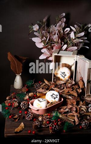 A vertical shot persimmon fruits on a table decorated with pines and dried leaves Stock Photo