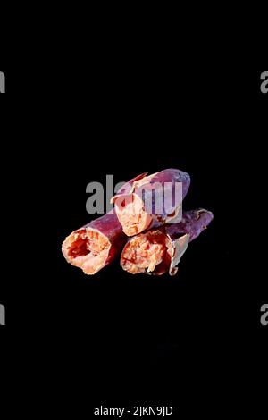 A vertical shot of sweet potatoes isolated on a black background Stock Photo