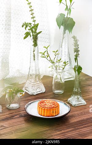 The vertical shot of a biscuit cake on a plate and with glass Eiffel shape plant vases on a table Stock Photo