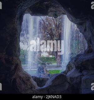 A silk effect water falling down in a park seen through a stone cave ...