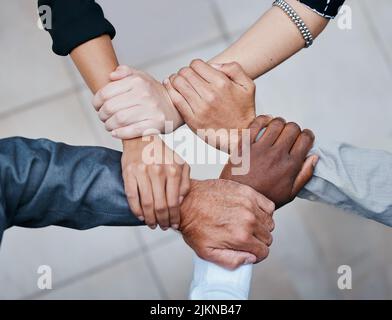 A diverse team makes for a better team. a group of unrecognizable businesspeople linking arms. Stock Photo