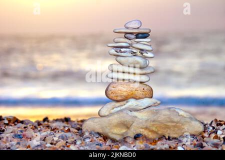 A closeup shot of balanced stone pyramide on shore of the ocean at dawn. Stock Photo