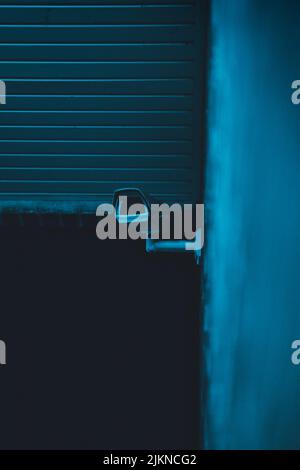 A vertical shot of a security camera on the wall at night Stock Photo