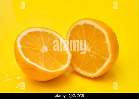 Two slices of lemon cut in half on yellow background Stock Photo