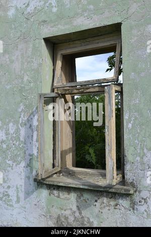 Broken old window with dilapidated antique vintage decorative white wooden frame mounted on cracked family house wall. Stock Photo