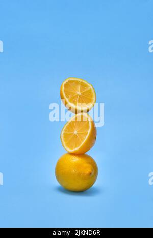 Lemon and sliced pieces stand on top of each other on blue background , concept Stock Photo