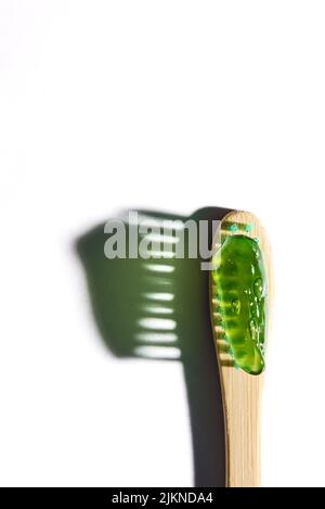 A closeup photo of a bamboo toothbrush with mint green bristle and toothpaste on white background Stock Photo