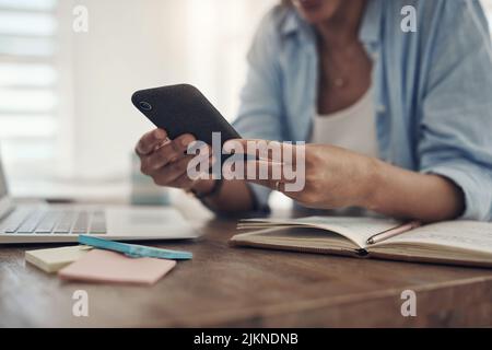 Whats happening on social media. an unrecognizable woman sitting alone at home and using her cellphone. Stock Photo