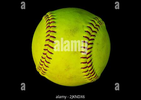 A closeup photo of a used softball isolated on a black background Stock Photo