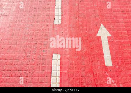 A photo of an arrow sign on red cycle path Stock Photo