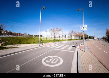 A photo of a road with road marking, street lamps and greenery in a city Stock Photo
