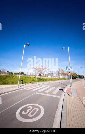 A vertical shot of a road with road marking, street lamps and greenery in a city Stock Photo