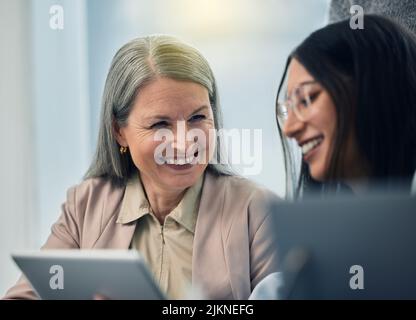 That was a hilarious video. a mature businesswoman using a digital tablet with her coworker. Stock Photo