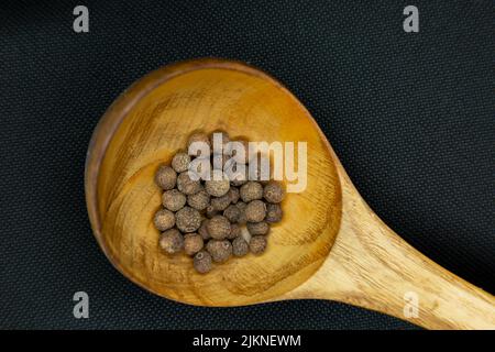 A top view shot of Organic Allspice Whole seeds on a wooden on a black background with a copy space Stock Photo