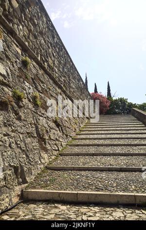 Cobbled passage and steps next to a stone wall in a castle on a sunny day Stock Photo