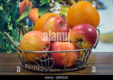 Oranges and apples on the table in a basket  in the background of a fruit tree Stock Photo