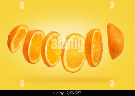 Floating slice of orange in close-up macro on a yellow background Stock Photo