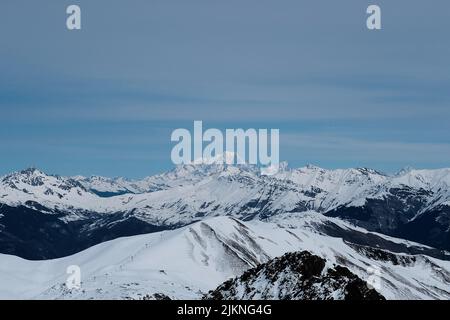 An aerial view of beautiful mountains covered in snow under a blue sky Stock Photo