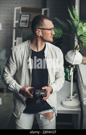 Portrait of professional man photographer standing in the office looking out the window posing by holding a camera. Positive person. Business portrait Stock Photo