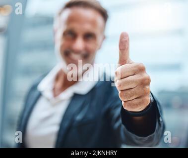 Youre getting better everyday. a mature businessman showing thumbs up against an urban background. Stock Photo