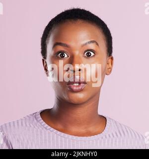 Thats shocking. Studio shot of a young woman looking shocked against a pink background. Stock Photo