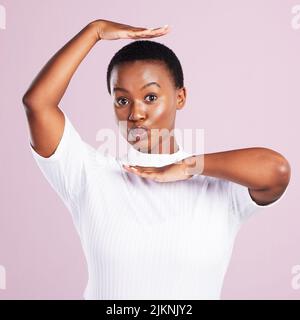 Picture perfect. Studio portrait of a young woman holding up her hands in a frame gesture against a pink background. Stock Photo