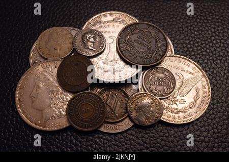 A closeup shot of a pile of Antique and ancient coinage on a leather black background Stock Photo