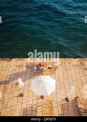 A high angle view of a man relaxing and sunbathing on the seaside terrace Stock Photo