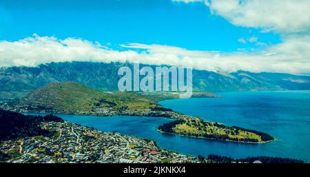 An aerial shot of Queenstown island in background of mountains in daylight Stock Photo