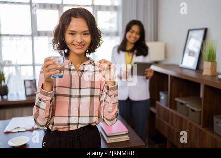 female patient holding medicine and a glass of drinking water Stock Photo