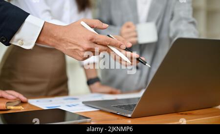 Cropped and focus hands image, A professional businessman or male boss explaining a financial data graph on the laptop screen to his team. Stock Photo