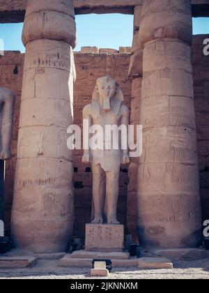 A vertical shot of a pharaoh statue between the columns in the Mortuary Temple of Hatshepsut in Egypt Stock Photo