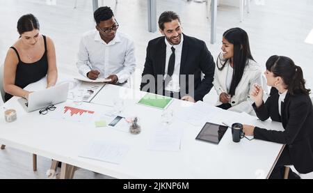 Their team dynamic works so well. High angle shot of a group of businesspeople brainstorming together in an office. Stock Photo