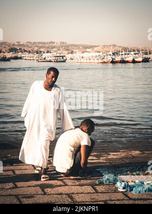 A vertical shot of a two egyptian men standing near Nile river, Egypt Stock Photo
