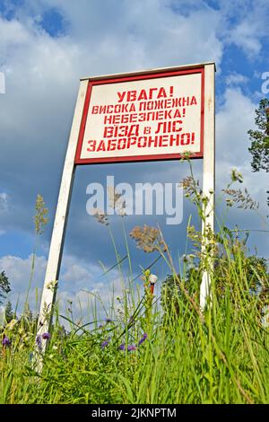 attention! high fire danger! no entrance to the forest! as red warning message on the wooden board on ukrainian language, blue thunderstorm sky with Stock Photo